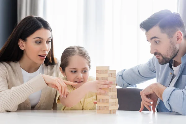 Mujer emocionada señalando con el dedo mientras juega bloques de madera juego con la familia - foto de stock