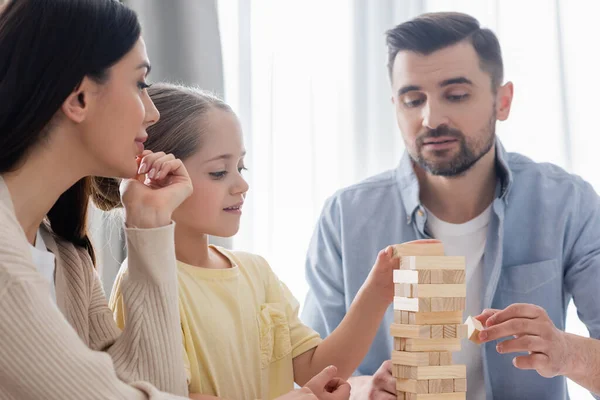 Couple with daughter playing wood tower game at home — Stock Photo