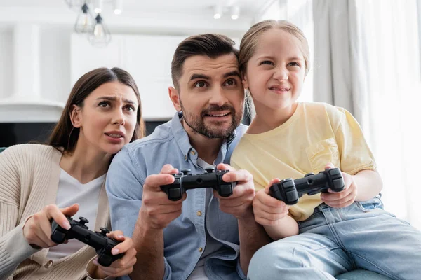 KYIV, UKRAINE - APRIL 8, 2021: focused parents with daughter gaming together at home — Stock Photo