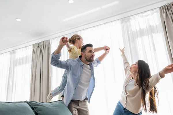 Glückliche Familie imitiert Fliegen und hat Spaß zu Hause — Stockfoto