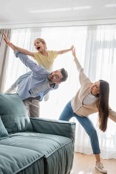 Allegra famiglia divertendosi mentre imita volare a casa — Foto stock