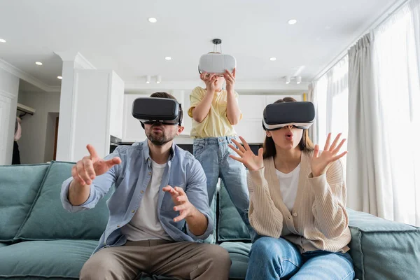 Famiglia eccitata gesticolando in cuffie vr in soggiorno — Foto stock