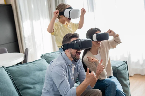 Happy family showing thumbs up and win gestures while gaming in vr headsets — Stock Photo