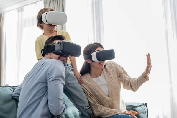 Woman gesturing while gaming in vr headsets with frightened family — Stock Photo