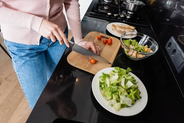 Vue recadrée de la femme coupant des tomates cerises près du filet de poulet frit tout en préparant le petit déjeuner — Photo de stock