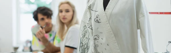 Foyer sélectif de kimono avec dessin traditionnel près des concepteurs flous en atelier, bannière — Photo de stock