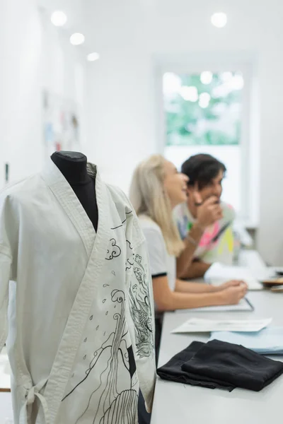 Enfoque selectivo de kimono con patrón cerca de diseñadores de moda riendo sobre fondo borroso - foto de stock