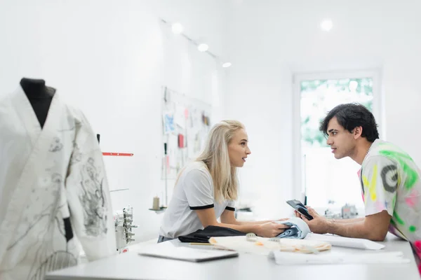 Fashion designers talking near mannequin in kimono on blurred foreground — Stock Photo