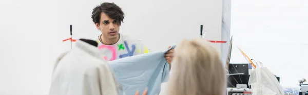 Diseñador de moda mostrando muestra de textil a colega en primer plano borrosa, bandera - foto de stock