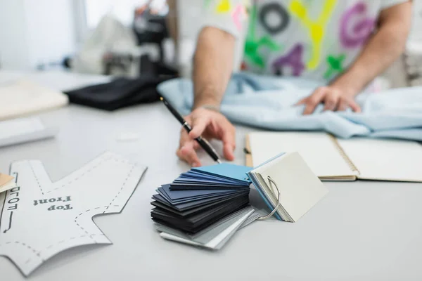 Teilansicht des verschwommenen Designers mit Stift in der Nähe von Schnittmuster und Farbpalette — Stockfoto