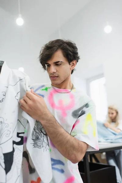 Elegante diseñador de moda tocando kimono en el maniquí cerca borrosa colega - foto de stock