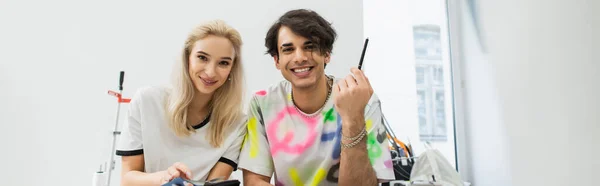 Jeunes designers branchés souriant à la caméra dans un atelier de mode, bannière — Photo de stock