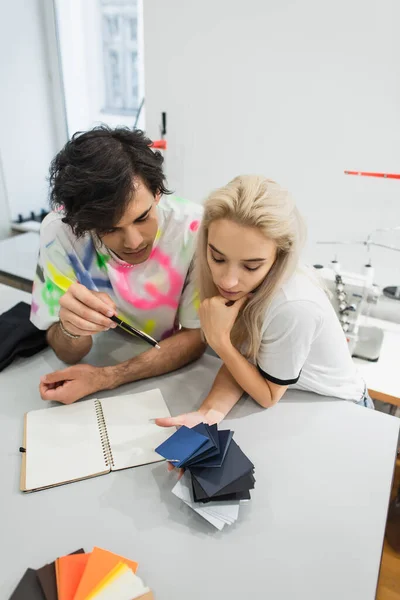 Hochwinkelaufnahme des Designers, der auf Farbmuster in den Händen eines Kollegen zeigt — Stockfoto