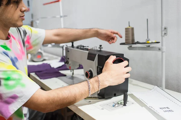 Vista ritagliata di giovane sarto regolazione macchina da cucire in officina di moda — Foto stock