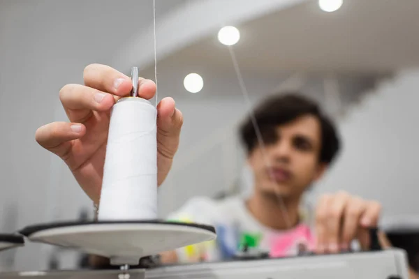 Blurred tailor adjusting thread spool on sewing machine in tailor shop — Stock Photo