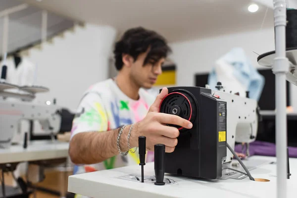 Young blurred tailor regulating sewing machine in fashion workshop — Stock Photo