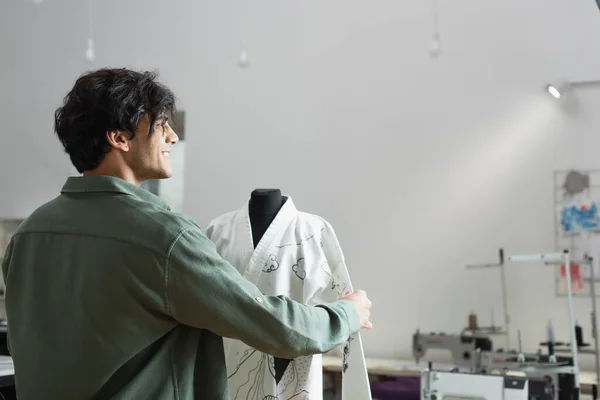 Happy fashion designer standing near kimono with traditional drawing on mannequin — Stock Photo