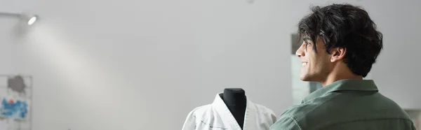 Diseñador de moda alegre sonriendo cerca de kimono en el maniquí en atelier, bandera - foto de stock