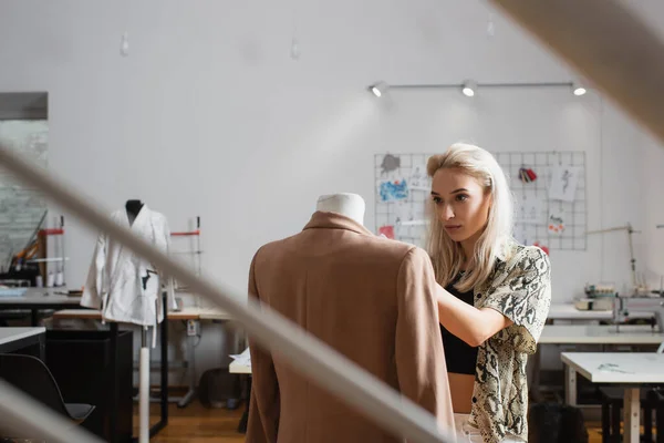 Joven, diseñador de moda rubia cerca del maniquí en atelier - foto de stock