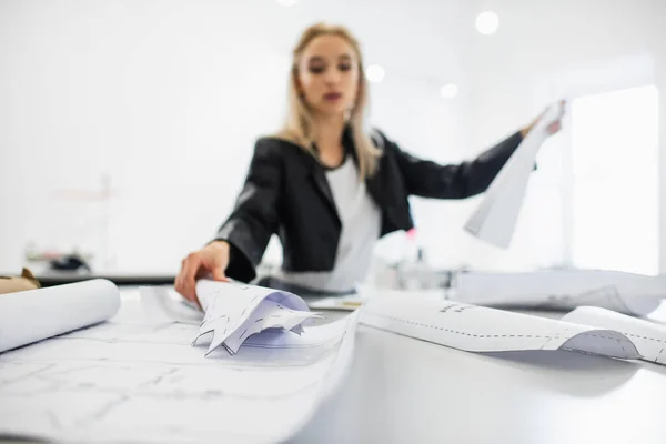 Diseñador de moda borrosa trabajando con patrones de costura en el lugar de trabajo - foto de stock