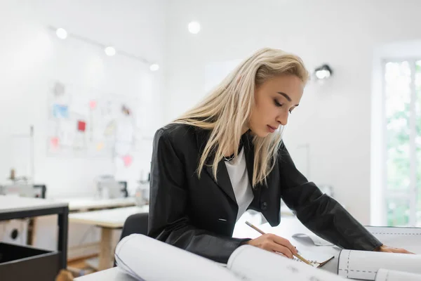 Créatif créateur de mode écriture dans un carnet près de modèles de couture sur le lieu de travail — Photo de stock