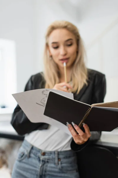 Pensée floue de créateur de mode tout en regardant croquis et carnet en atelier — Photo de stock