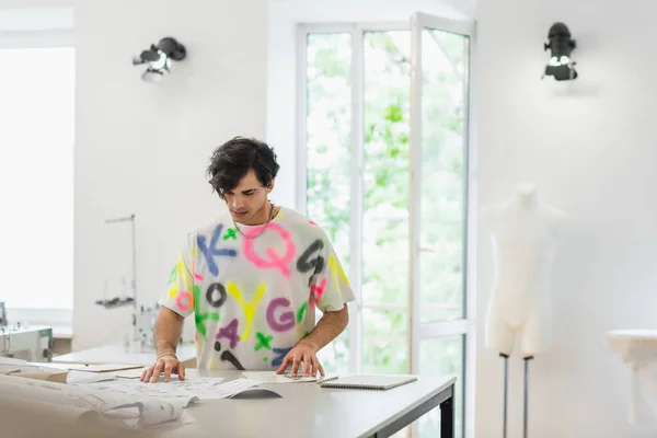 Moda designer de moda olhando para esboços e padrões de costura no atelier — Fotografia de Stock