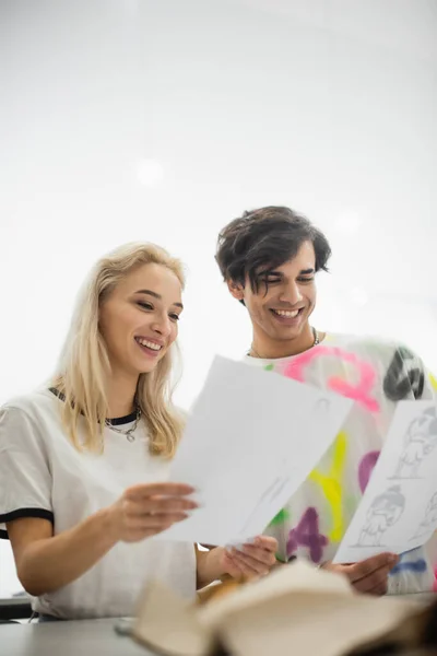Радісний дизайнер, дивлячись на малюнки в ательє на розмитому фоні — Stock Photo