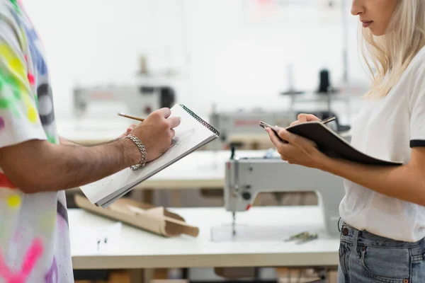 Vista recortada de los jóvenes diseñadores de moda escribir y dibujar en cuadernos - foto de stock