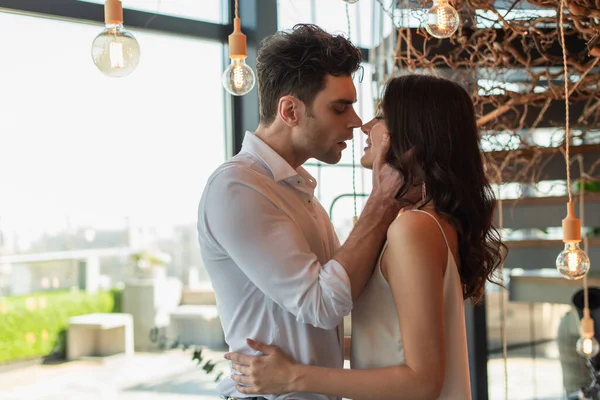 Seitenansicht eines Mannes, der junge brünette Frau in Restaurant umarmt — Stockfoto