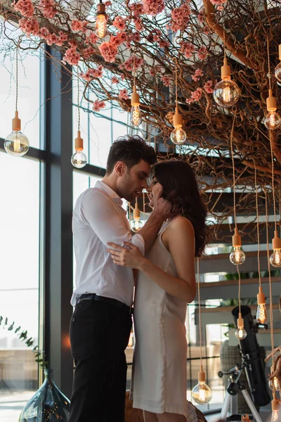 Vue latérale d'un homme passionné embrassant une jeune femme brune dans un restaurant — Photo de stock