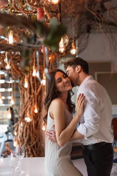 Man kissing cheerful young woman in restaurant — Stock Photo