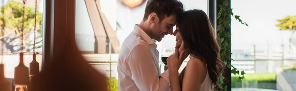 Vista laterale di uomo e donna che sorridono mentre si abbracciano nel ristorante, banner — Foto stock