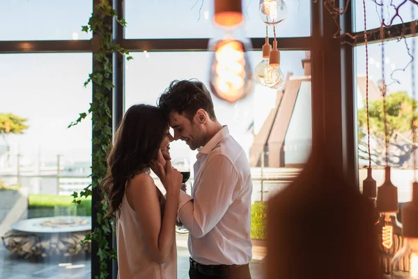 Side view of man and woman smiling while hugging in restaurant — Stock Photo