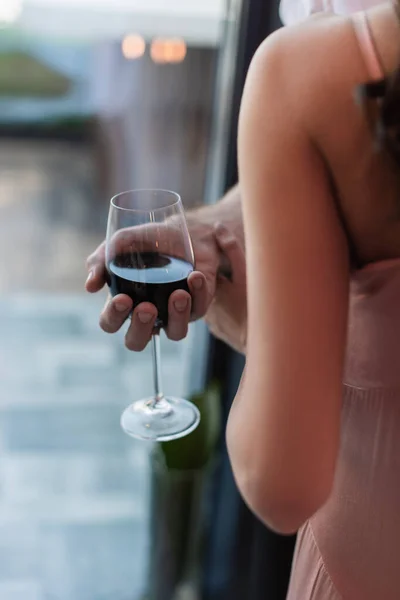 Обрезанный вид мужчины, держащего бокал красного вина рядом с женщиной — стоковое фото