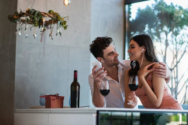 Happy couple in wireless earphones looking at each other — Stock Photo