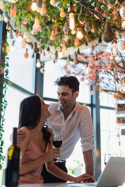 Casal feliz olhando uns para os outros perto de laptop na mesa — Fotografia de Stock