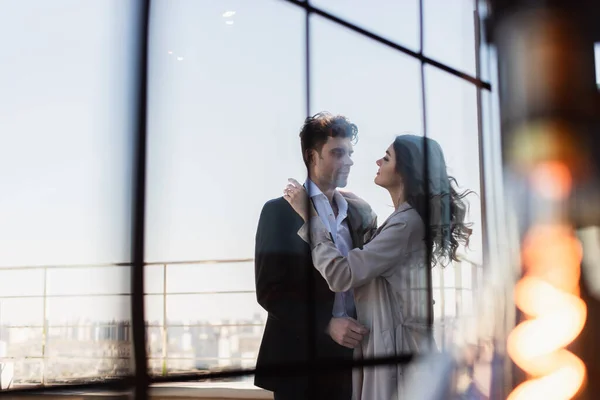 Couple étreignant sur la terrasse derrière la fenêtre floue du restaurant — Photo de stock