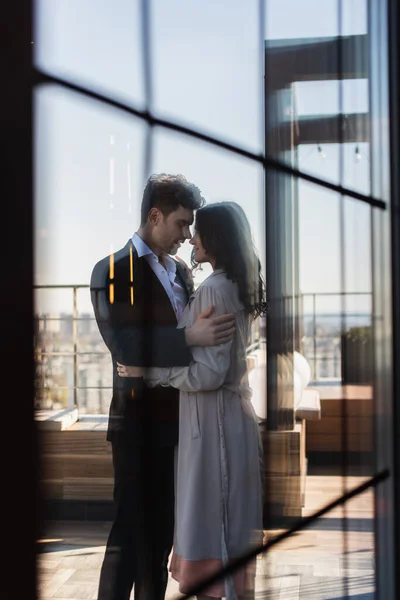 Feliz pareja abrazándose en la terraza detrás de ventana borrosa del restaurante — Stock Photo