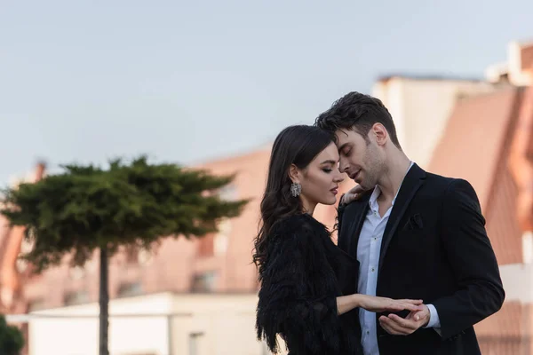 Hombre abrazo mujer en vestido y chaqueta de piel sintética en la terraza del restaurante - foto de stock