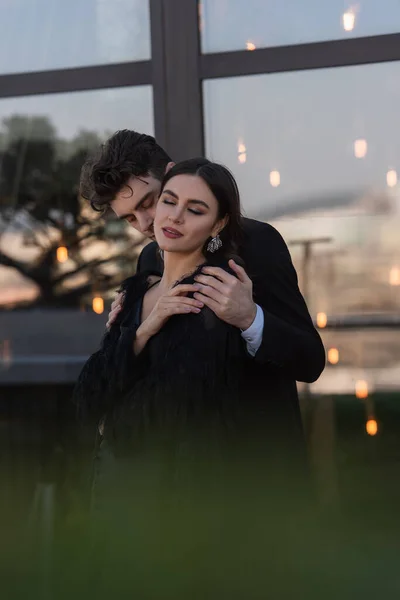 Homem abraçando mulher elegante no falso casaco de pele ao ar livre — Fotografia de Stock