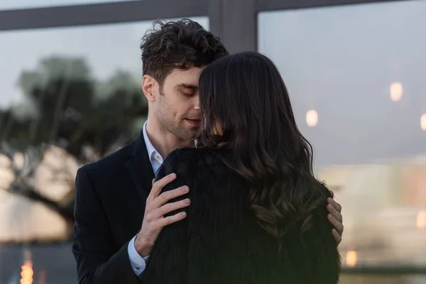 Man hugging brunette woman in faux fur jacket outdoors — Stock Photo