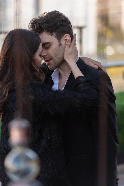 Woman in faux fur jacket embracing man in suit outdoors — Stock Photo