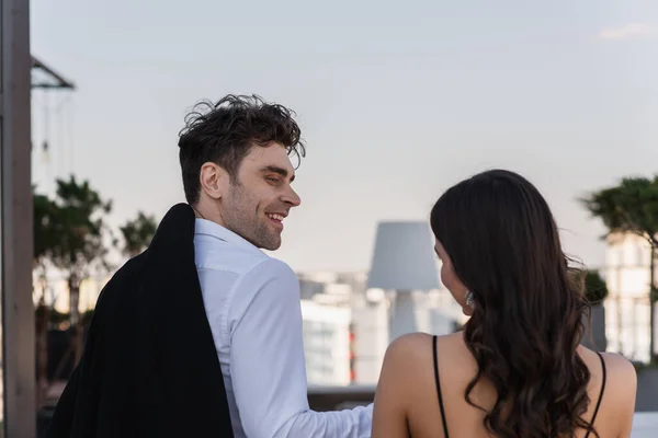 Hombre feliz mirando morena novia en terraza - foto de stock