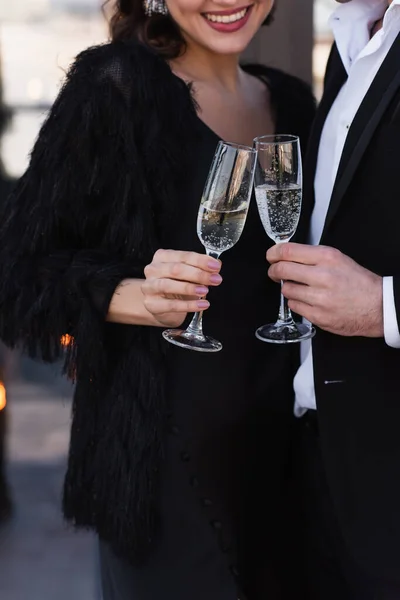 Vue recadrée de l'homme et de la femme heureuse cliquetis verres de champagne — Photo de stock