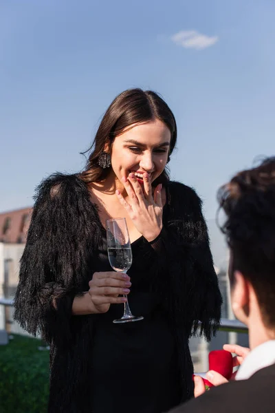 Homem fazendo proposta para mulher animado com copo de champanhe — Fotografia de Stock