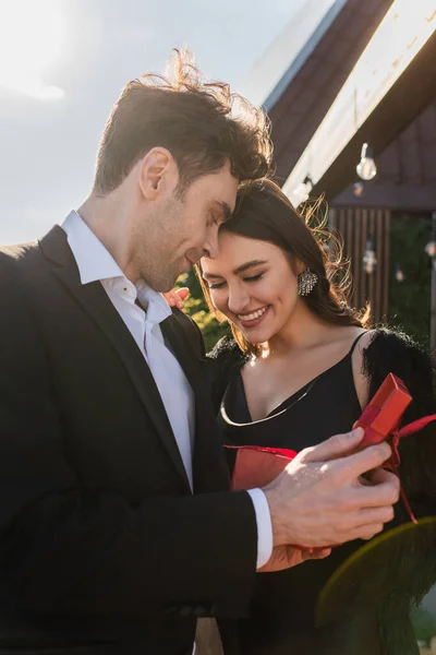 Felice uomo tenendo presente vicino donna sorridente sulla terrazza — Foto stock