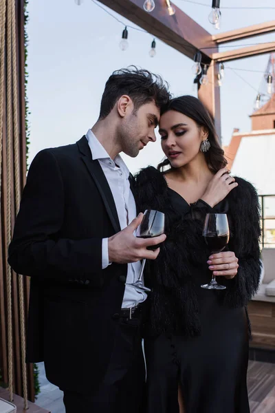 Mulher elegante e homem segurando copos de vinho no terraço — Fotografia de Stock