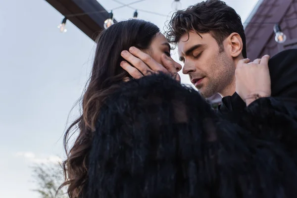 Low angle view of man hugging woman in faux fur jacket — Stock Photo