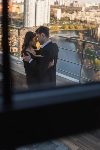 Vista lateral del hombre abrazando a la mujer elegante en el techo — Stock Photo